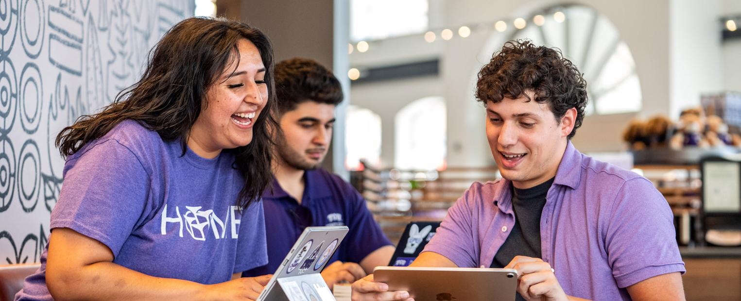 TCU students socialize at a table by the Starbucks kiosk in the TCU Campus Store.