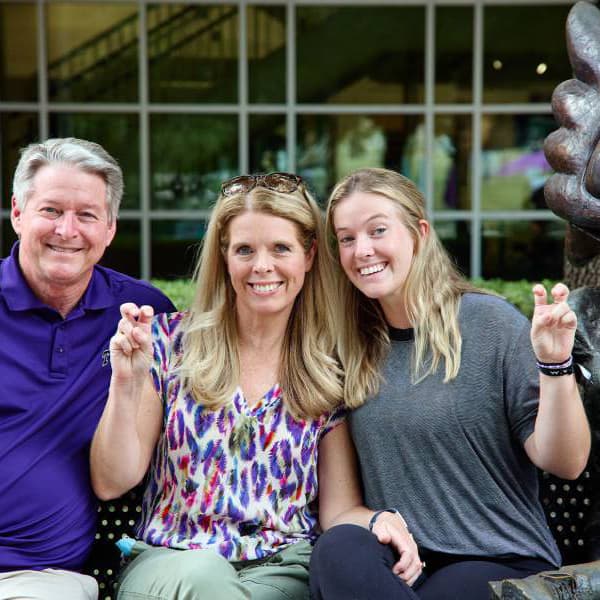 Father, mother, and daughter posing next to Super Frog statue