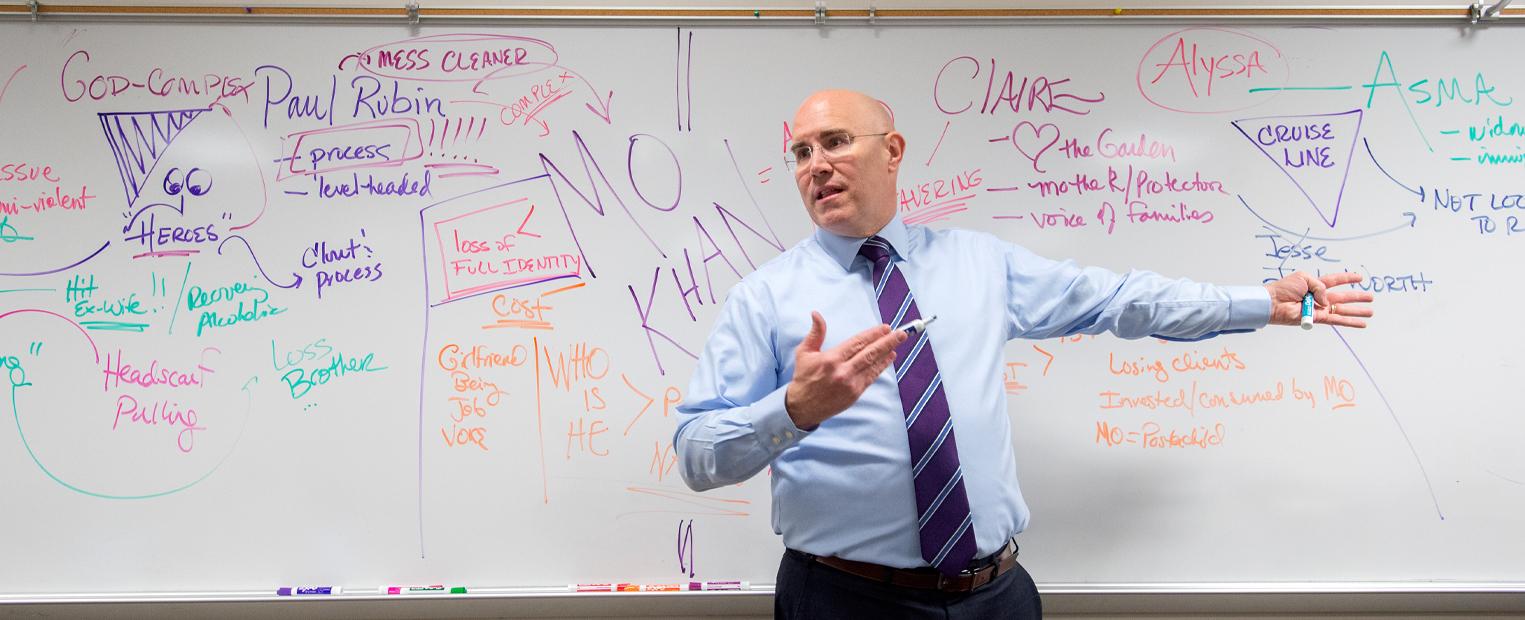 Professor making notes on a dry erase board