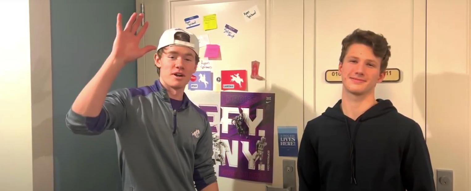 two boys standing in front of decorated dorm room door 