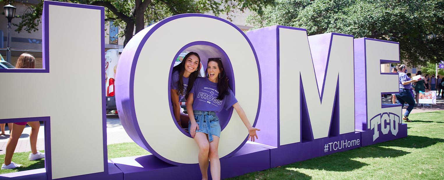 students smiling with large letters spelling HOME