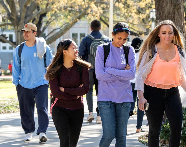 students walking on campus wearing backpacks