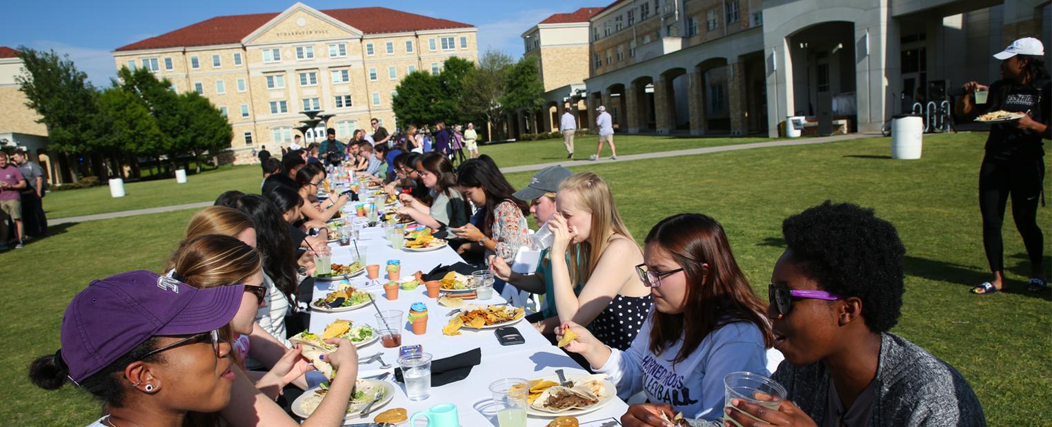 Students eating at a large table in the campus commons at TCU's Common Table event 