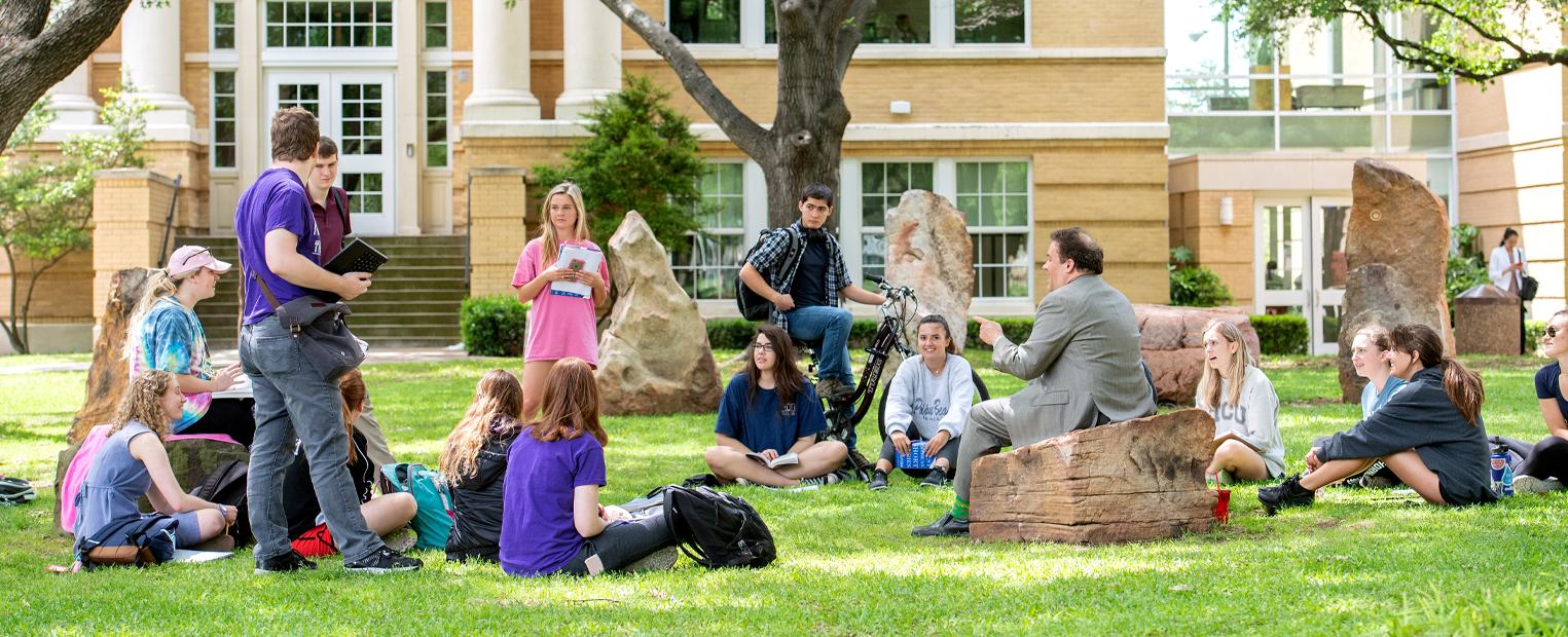 students and a professor gathered at frog henge for class 