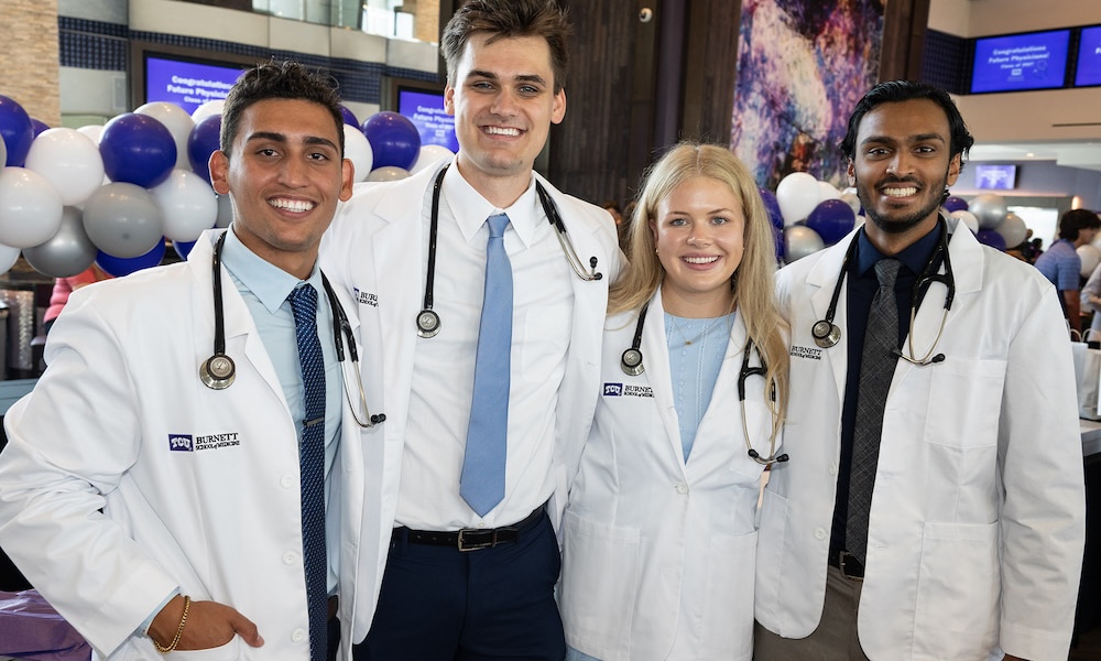 Four students in white coats pose for photo