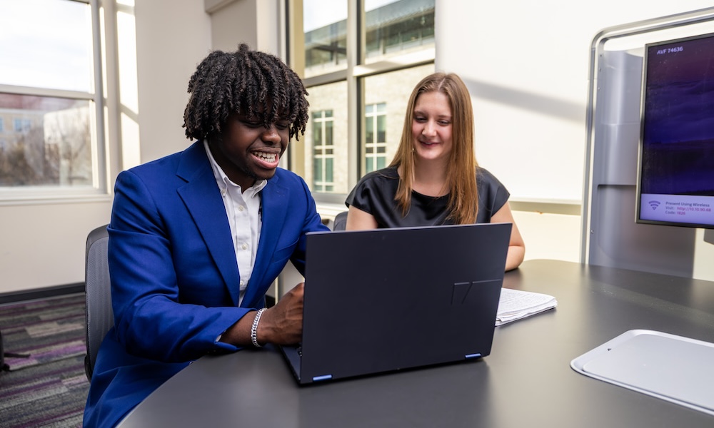 Two people look at laptop screen