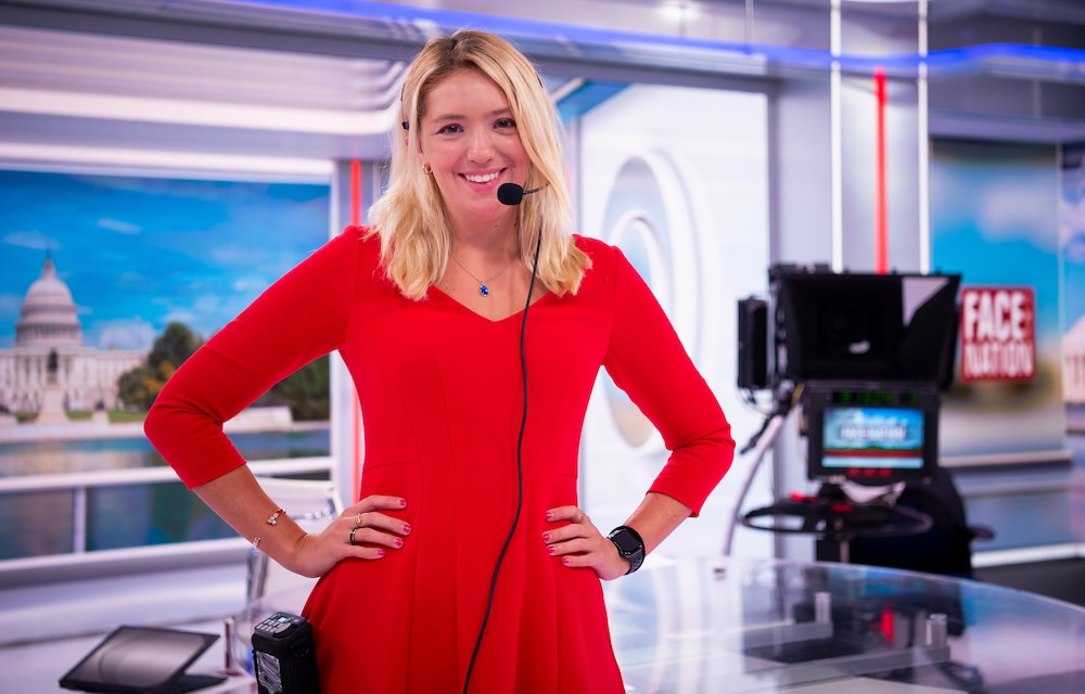 A woman in a red dress wears a headset on television set
