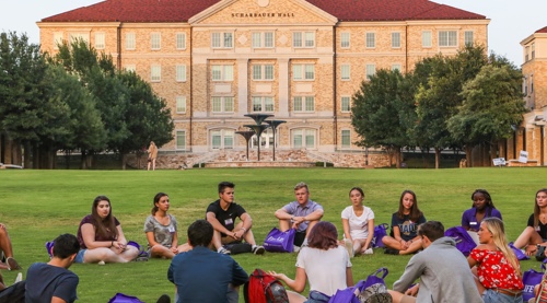 Students sitting in a circle on commons lawn area