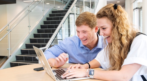 Male and female students using laptop computer