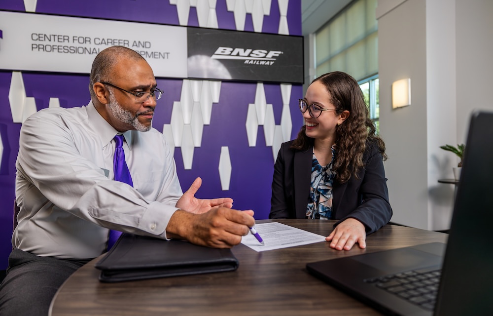 A man in a tie talks to a woman in a suit at a table